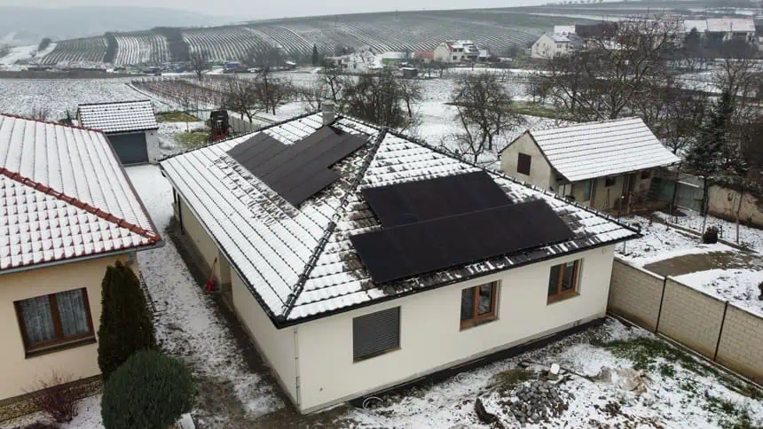 Výškové práce při montáži solárních panelů na zasněžené střeše domu